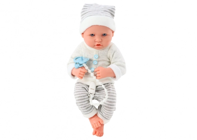 Levensechte babypop in wit-grijze outfit met muts en fopspeen
