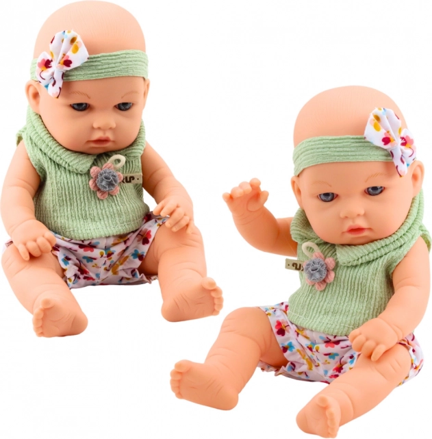 Babypop in groene outfit met bloemenpatroon en haarband met strik