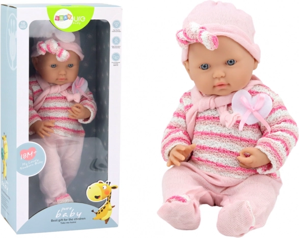 Baby doll in a pink striped cardigan with bonnet and scarf